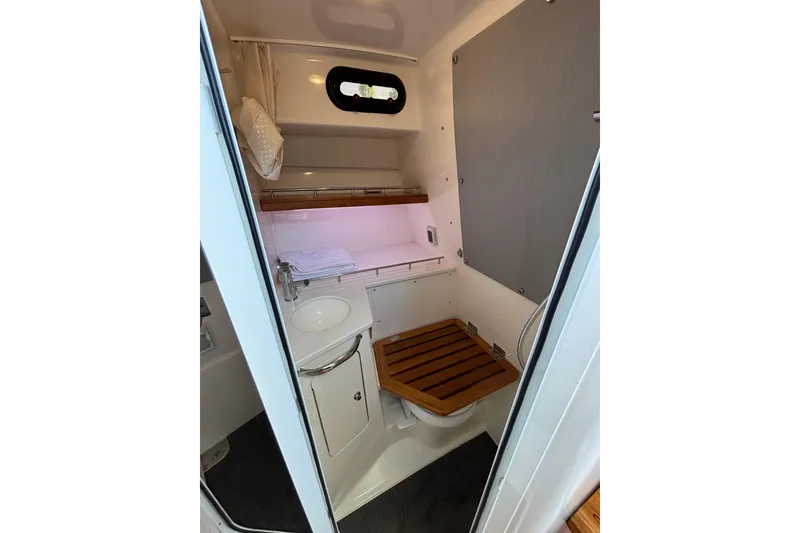 Slide: The Image of 2024 Boston Whaler 350 Realm interior cabin with sink, toilet, and wooden seat. - 36