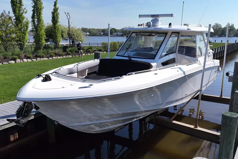 Slide: The Image of 2024 Boston Whaler 350 Realm boat docked by a scenic waterfront. - 48