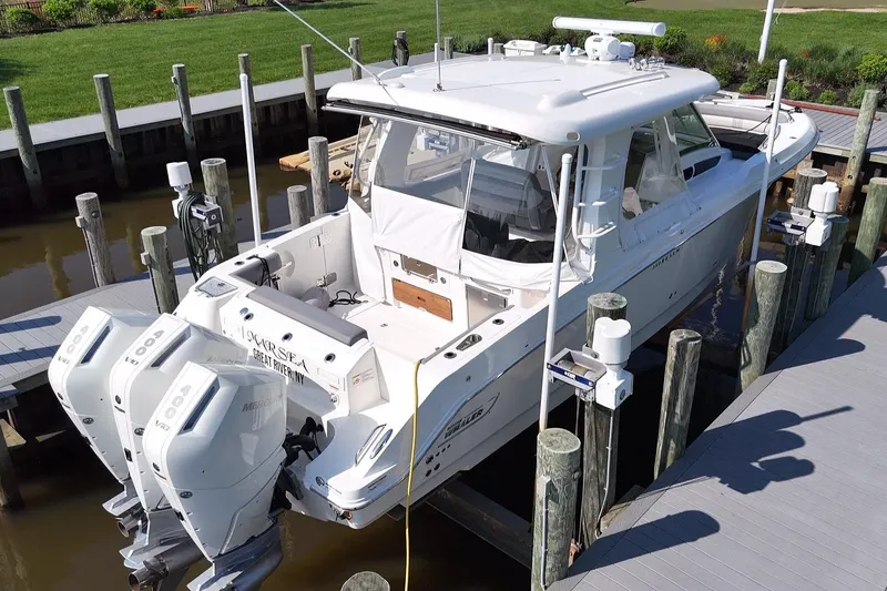 Slide: The Image of 2024 Boston Whaler 350 Realm docked, featuring triple Mercury outboard engines. - 49