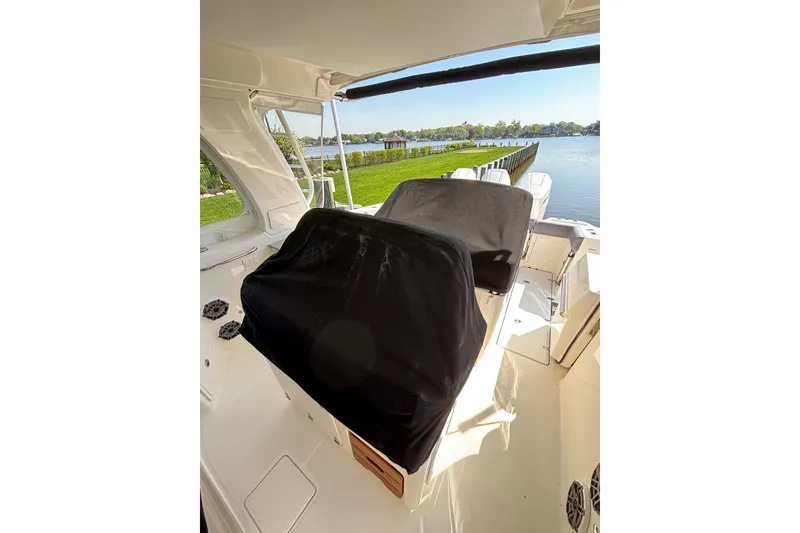 Slide: The Image of 2024 Boston Whaler 350 Realm cockpit with covered seating, overlooking serene waterfront. - 53