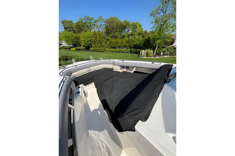 Slide: The Image of 2024 Boston Whaler 350 Realm boat interior with black cover, surrounded by lush greenery. - 55