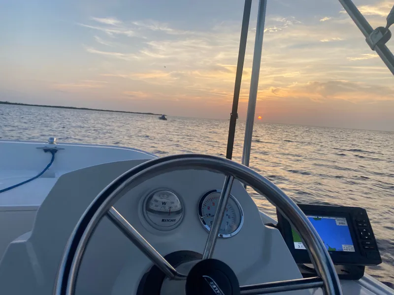 Slide: The Image of The helm of a 2018 Boston Whaler 150 Super Sport at sunset on the water. - 22