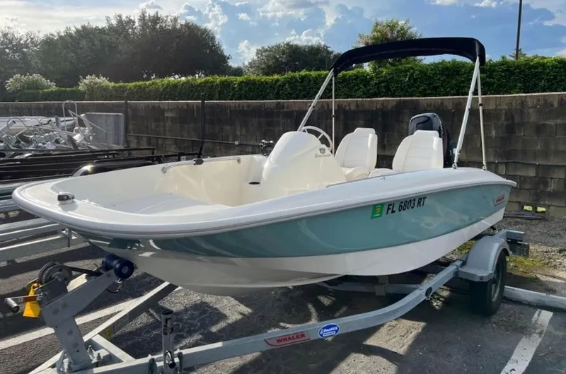 Slide: The Image of A 2018 Boston Whaler 150 Super Sport on a trailer, featuring a blue hull and bimini top. - 1