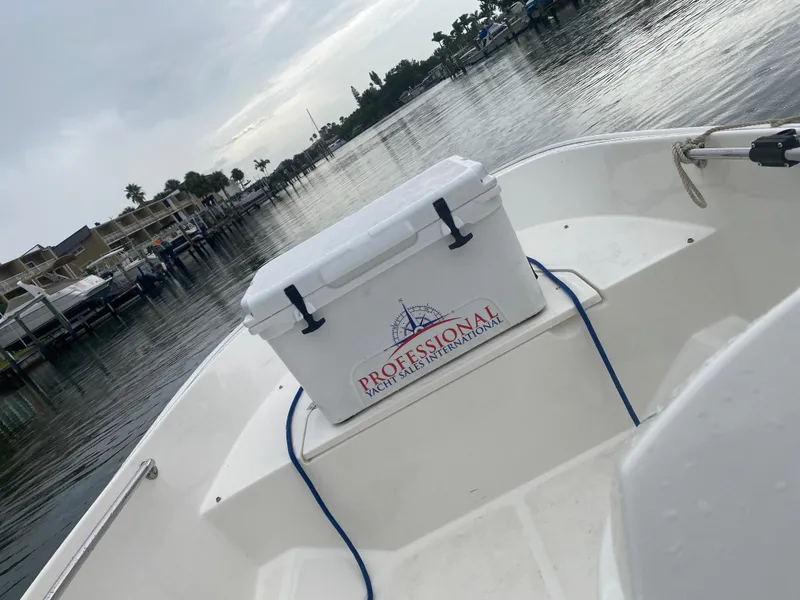 Slide: The Image of A 2018 Boston Whaler 150 Super Sport on calm water. A cooler is on board. - 16