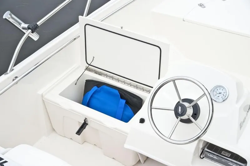 Slide: The Image of The image shows the cockpit of a 2018 Boston Whaler 150 Super Sport with a blue bag in storage. - 32