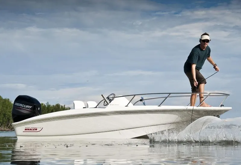 Slide: The Image of A man stands on a 2018 Boston Whaler 150 Super Sport on calm water. - 27