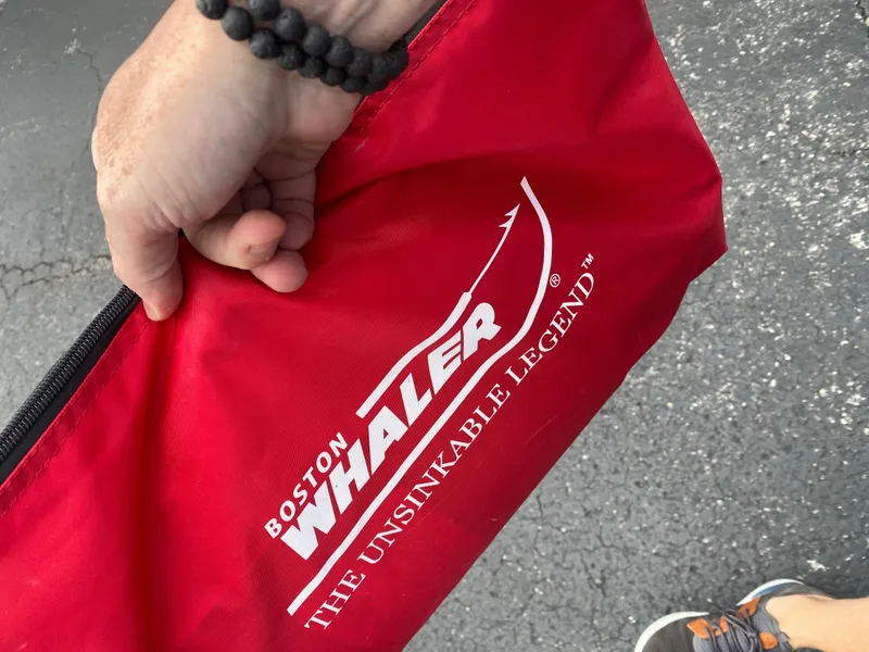 Slide: The Image of A hand holds a red bag with the Boston Whaler logo and the slogan "The Unsinkable Legend." - 23