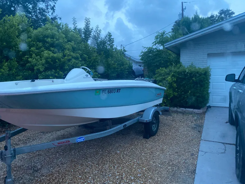 Slide: The Image of A 2018 Boston Whaler 150 Super Sport on a trailer in a driveway. - 11