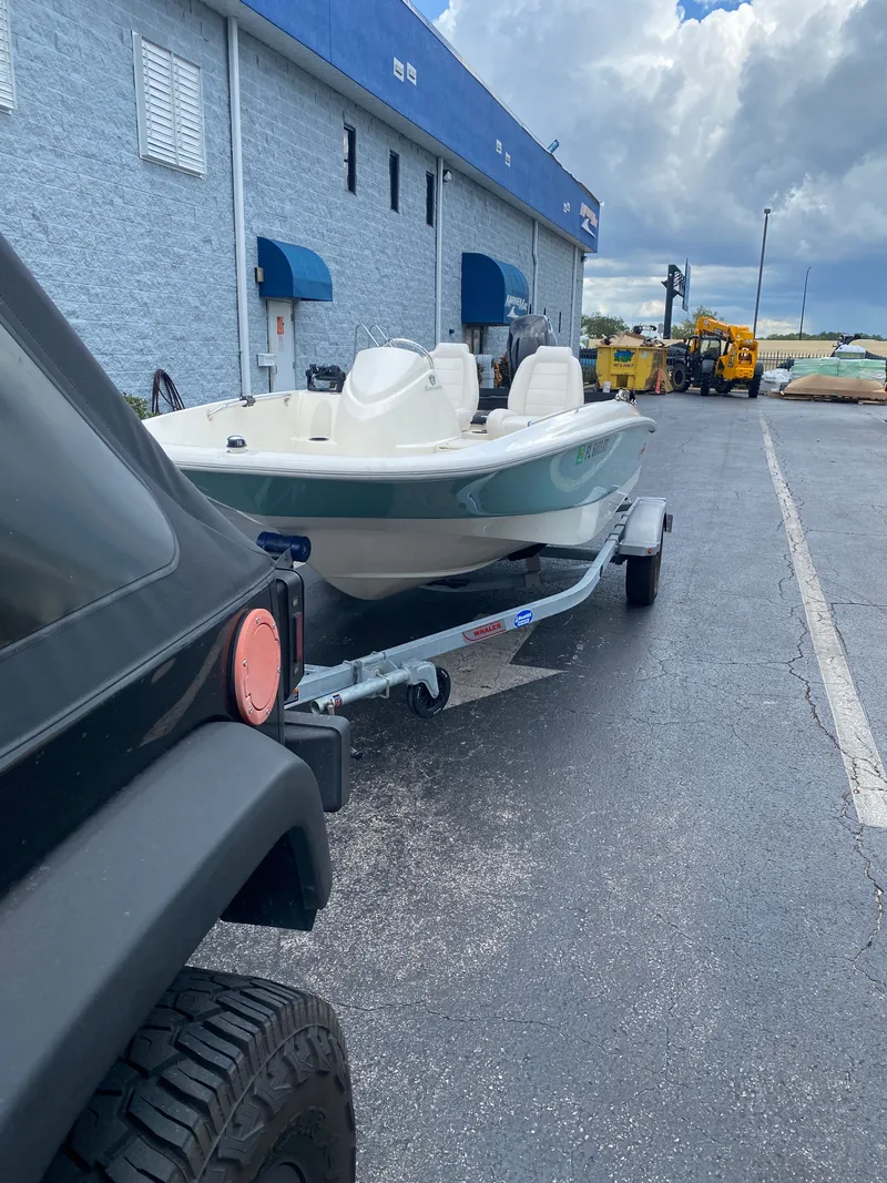 Slide: The Image of 2018 Boston Whaler 150 Super Sport on trailer, parked beside a building. - 9