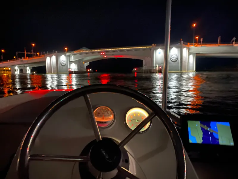 Slide: The Image of The image shows the helm of a 2018 Boston Whaler 150 Super Sport at night. A lit bridge is visible in the background. - 19