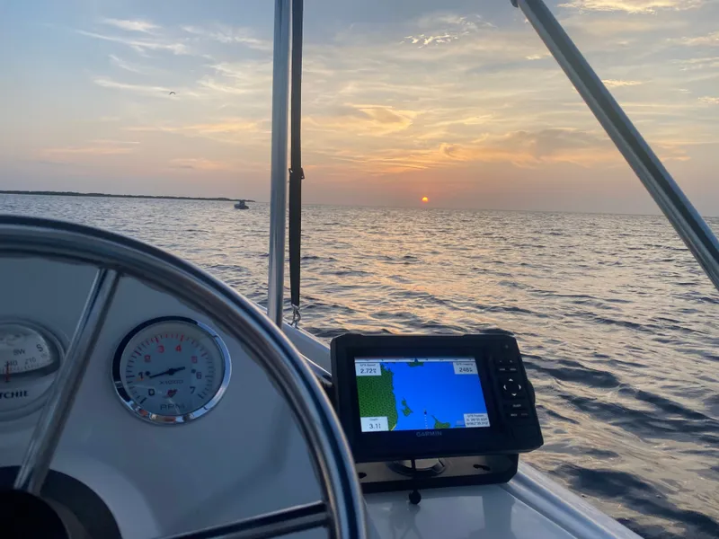 Slide: The Image of A 2018 Boston Whaler 150 Super Sport on the water at sunset, featuring a navigation system. - 21