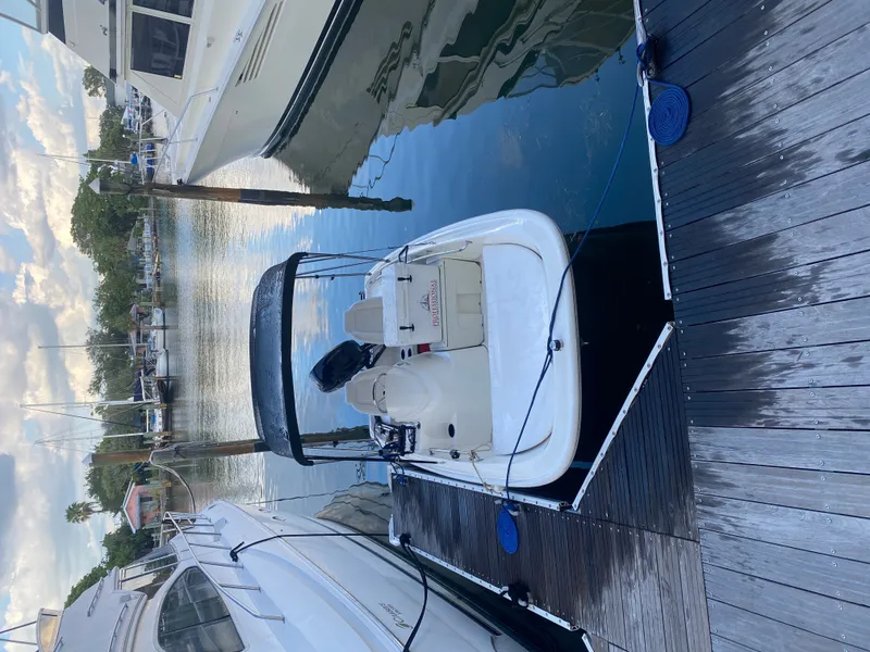 Slide: The Image of A 2018 Boston Whaler 150 Super Sport is docked. It features a sleek, white design. - 14