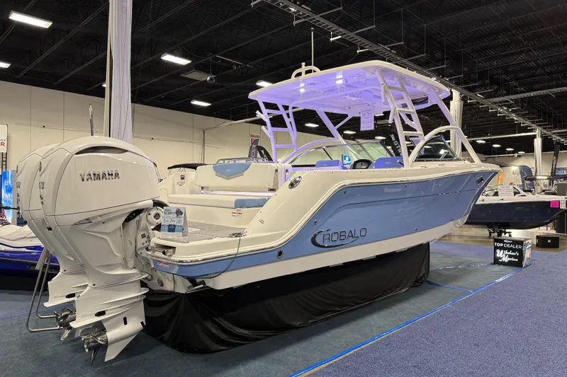 Slide: The Image of 2026 Robalo R317 Dual Console boat displayed indoors with Yamaha engines. - 2
