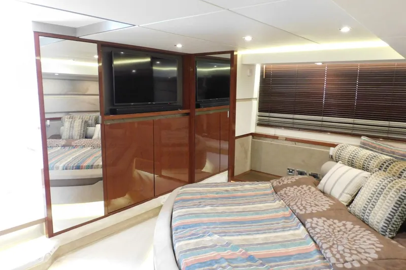 Slide: The Image of Luxurious 2019 Sea Ray L550 yacht bedroom with striped bedding and wooden cabinetry. - 39