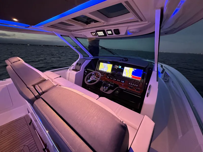 Slide: The Image of 2020 Tiara Yachts 43 LS helm with illuminated dashboard and ocean view at dusk. - 16
