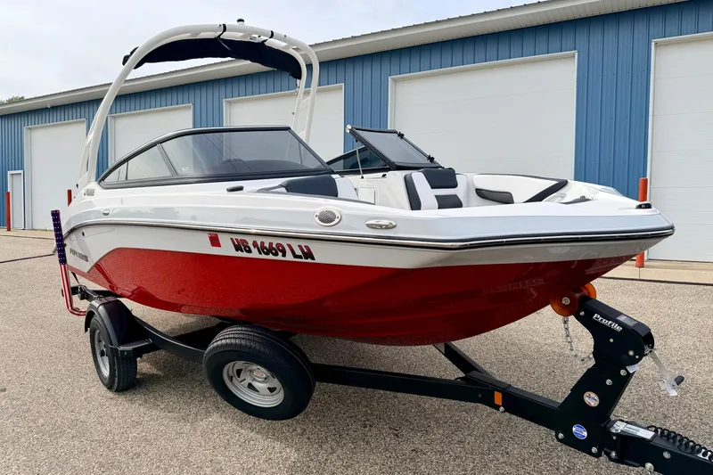 Slide: The Image of 2024 Yamaha AR195 boat with red hull on trailer, parked near blue building. - 3