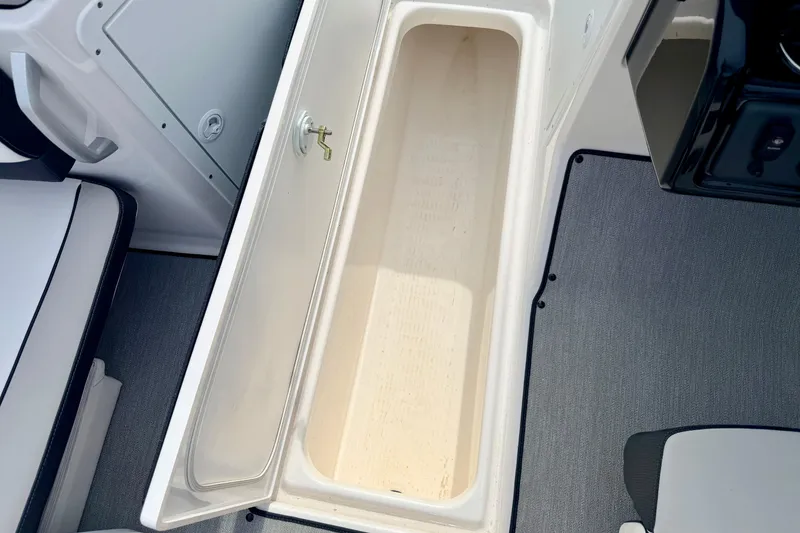 Slide: The Image of 2024 Yamaha AR195 boat storage compartment with open lid, showcasing interior space. - 48