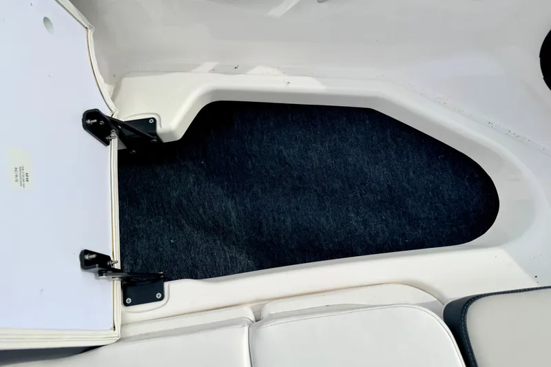Slide: The Image of 2024 Yamaha AR195 boat interior storage compartment with open hatch and carpeted floor. - 51