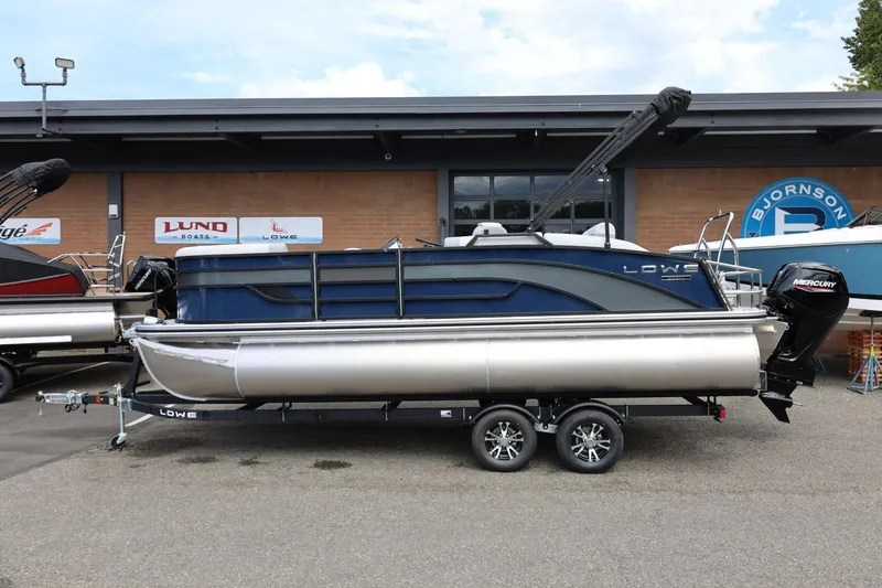 The Image of 2026 Lowe SS 210 CL pontoon boat on trailer, displayed outside dealership. - 1