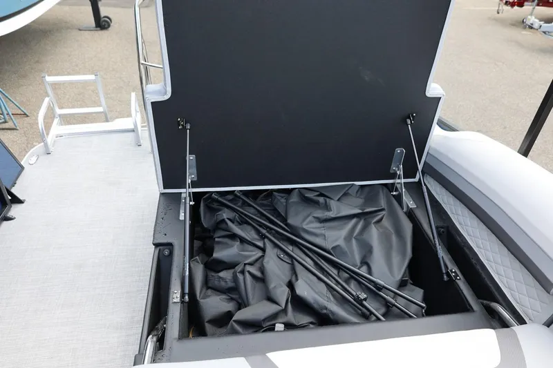 Slide: The Image of Open storage compartment on 2026 Lowe SS 210 CL boat, revealing black cover and poles. - 20