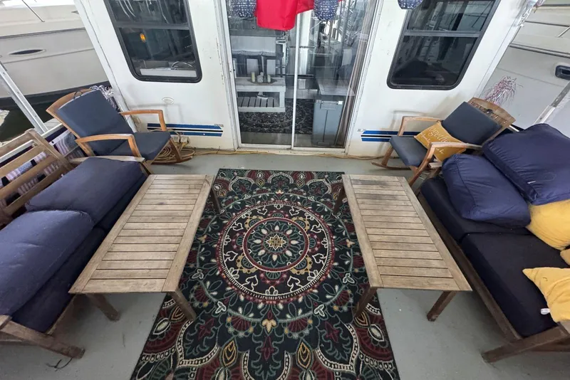 Slide: The Image of Outdoor seating area on 2006 Catamaran Cruisers Aqua Cruiser Executive, featuring wooden furniture and patterned rug. - 7