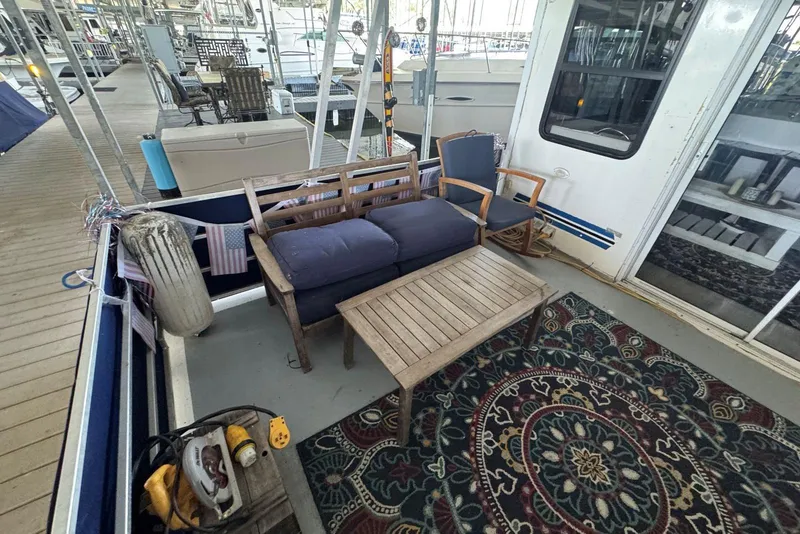 Slide: The Image of Outdoor seating area on 2006 Catamaran Cruisers Aqua Cruiser Executive, featuring wooden furniture and decorative rug. - 9