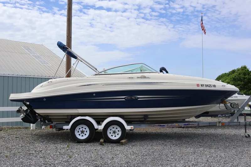 The Image of 2007 Sea Ray 220 Sundeck boat on trailer, parked outdoors under a blue sky. - 0