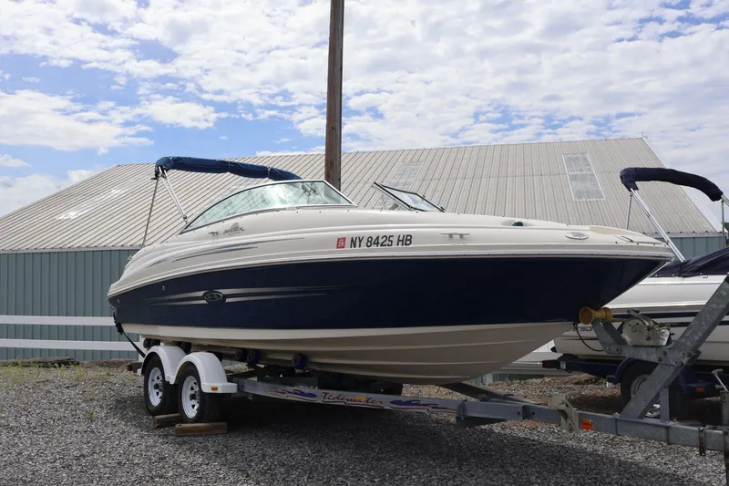 Slide: The Image of 2007 Sea Ray 220 Sundeck boat on trailer, parked outdoors under cloudy sky. - 2