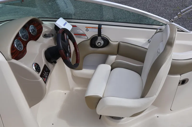 Slide: The Image of 2007 Sea Ray 220 Sundeck cockpit with steering wheel and gauges, featuring beige and white seating. - 23