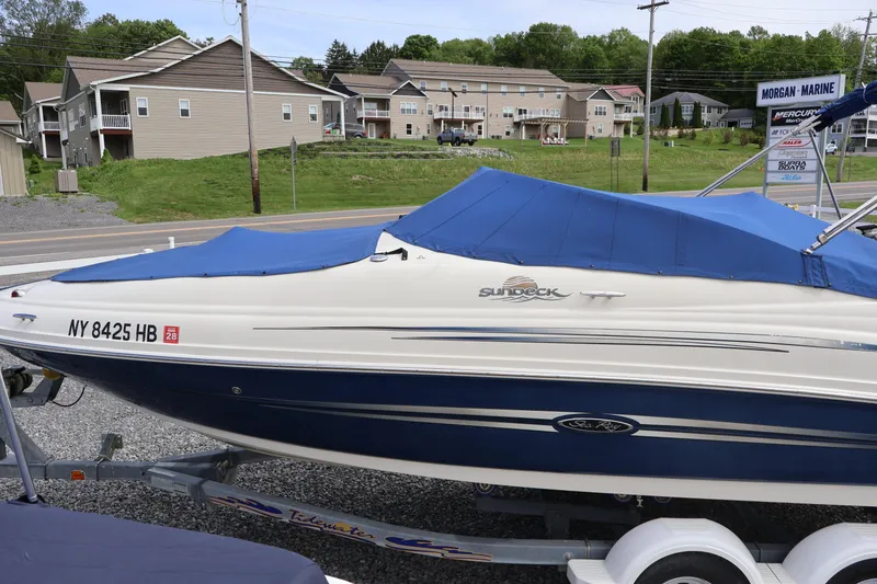Slide: The Image of 2007 Sea Ray 220 Sundeck boat with blue cover on trailer, parked near residential area. - 51