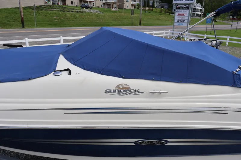 Slide: The Image of 2007 Sea Ray 220 Sundeck boat with blue cover, parked near a road. - 52