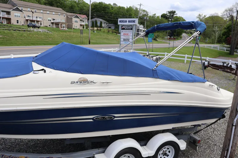 Slide: The Image of 2007 Sea Ray 220 Sundeck boat with blue cover on trailer, parked near road. - 54