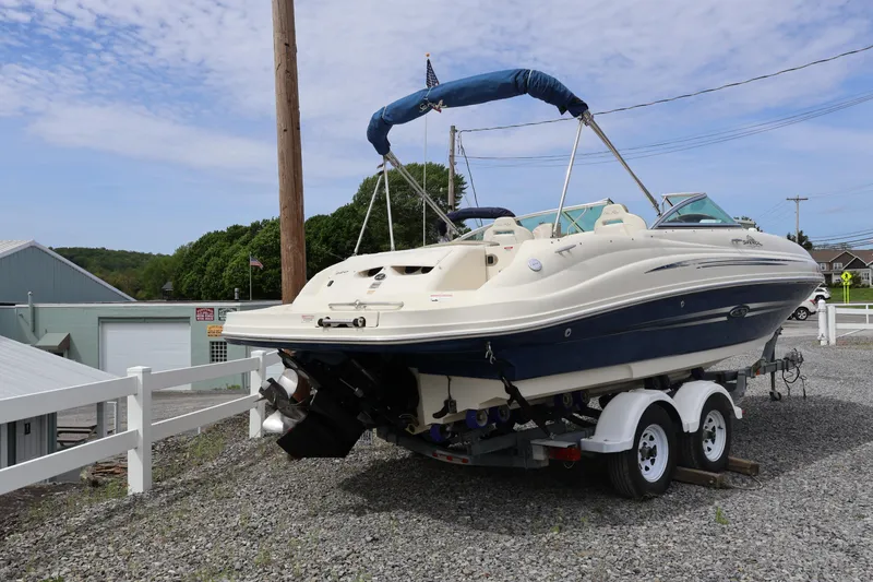 Slide: The Image of 2007 Sea Ray 220 Sundeck boat on trailer, parked outdoors under a blue sky. - 6