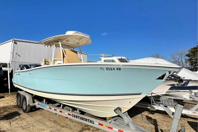 The Image of 2016 Cobia 277 Center Console boat on trailer, clear blue sky background. - 0