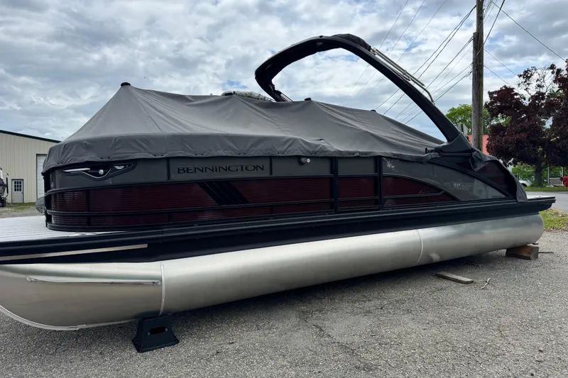 The Image of 2026 Bennington 23 M Center Swingback pontoon boat with cover, parked outdoors. - 0