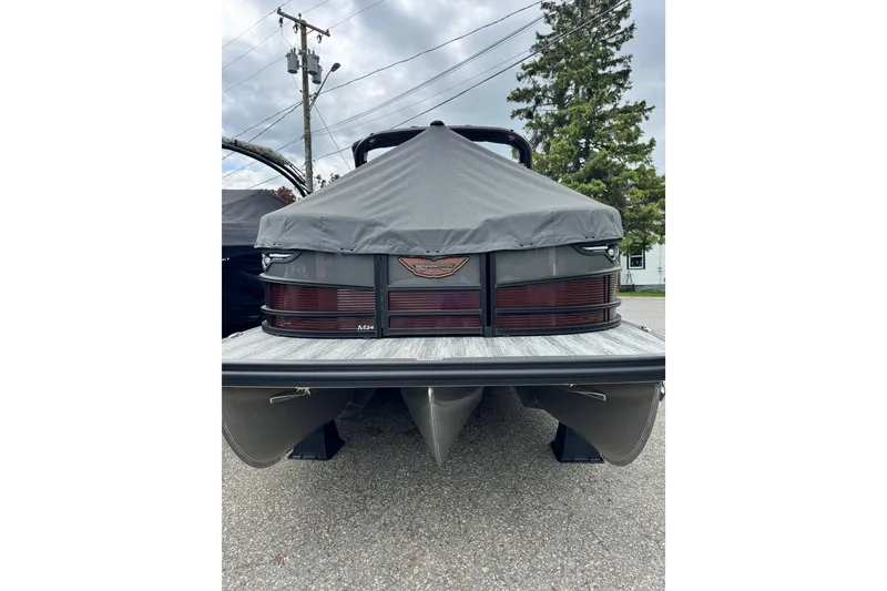 Slide: The Image of 2026 Bennington 23 M Center Swingback pontoon boat with cover, parked on pavement. - 2