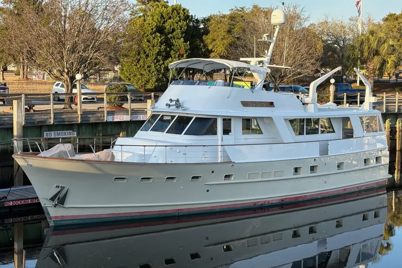 Slide: The Image of 1974 Burger 67 Motor Yacht docked, reflecting on calm water, surrounded by trees. - 2
