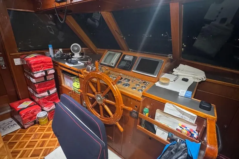 Slide: The Image of 1974 Burger 67 Motor Yacht helm with wooden wheel, navigation equipment, and stacked red life jackets. - 8