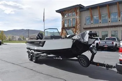 Slide: The Image of 2026 Lowe Fishing Machine 1875 boat on trailer, parked outside a building. - 12