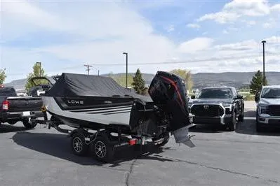 Slide: The Image of 2026 Lowe Fishing Machine 1875 boat on trailer, parked outdoors with cover. - 2