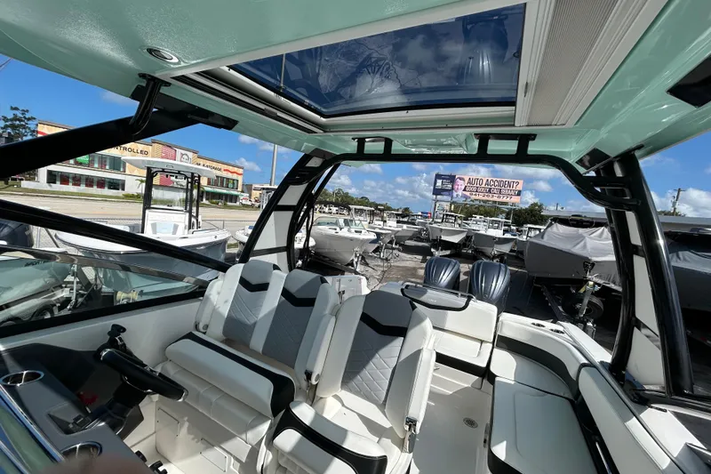 Slide: The Image of 2023 Chaparral 280 OSX boat interior with modern seating and dual engines, under a clear sky. - 15