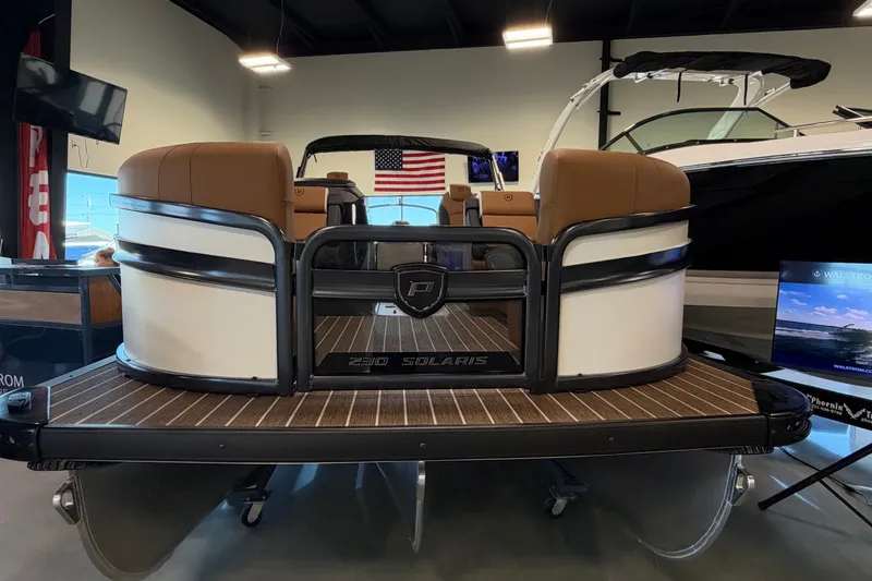 Slide: The Image of 2027 Premier 230 Solaris RF-CL pontoon boat displayed indoors with American flag backdrop. - 3