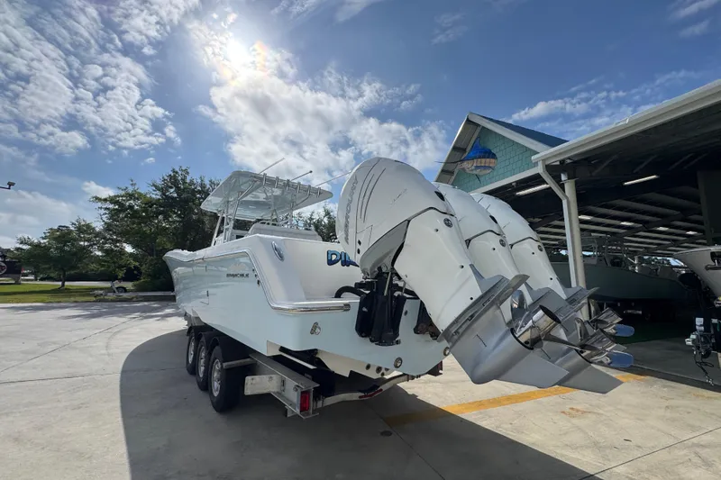 Slide: The Image of 2017 Invincible 39 Open Fisherman boat with triple outboard engines in a sunny marina. - 14