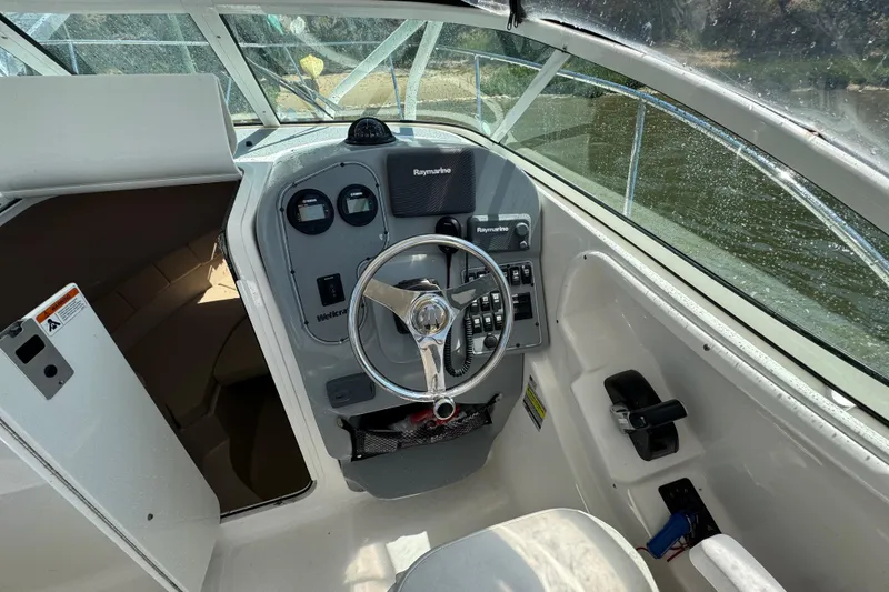 Slide: The Image of 2016 Wellcraft 252 Coastal boat cockpit with steering wheel and control panel. - 12