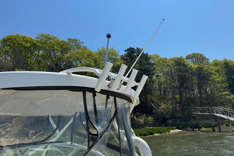 Slide: The Image of 2016 Wellcraft 252 Coastal boat with antennas, cruising near a wooded shoreline. - 19