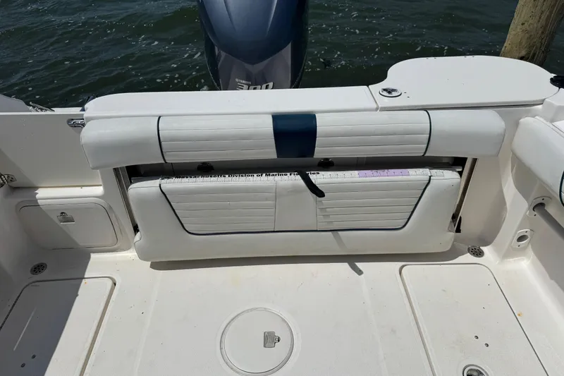 Slide: The Image of 2016 Wellcraft 252 Coastal boat interior with seating and storage, docked by water. - 24