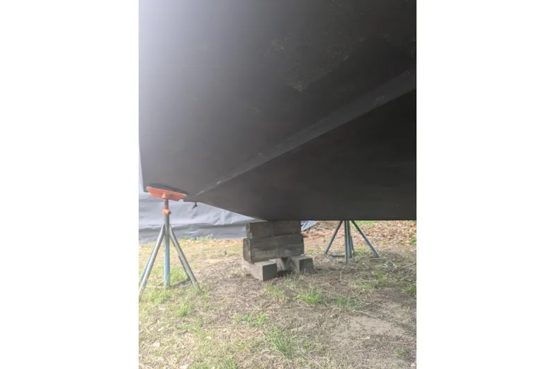 Slide: The Image of 2016 Wellcraft 252 Coastal boat hull supported by stands and blocks on grass. - 8