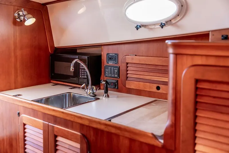 Slide: The Image of Hinckley Picnic Boat 36 Classic 2000 interior kitchen with sink, microwave, and wooden cabinetry. - 13