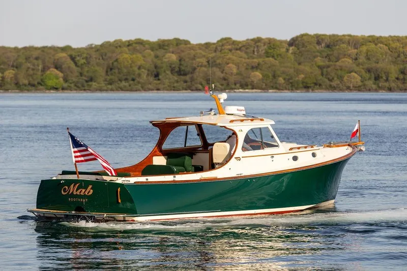 Slide: The Image of Hinckley Picnic Boat 36 Classic, 2000 model, cruising on calm waters with lush green shoreline. - 3