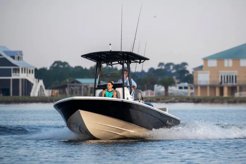 The Image of Manufacturer Provided Image: 2022 NauticStar 227 Bay boat cruising on water near coastal homes. - 0